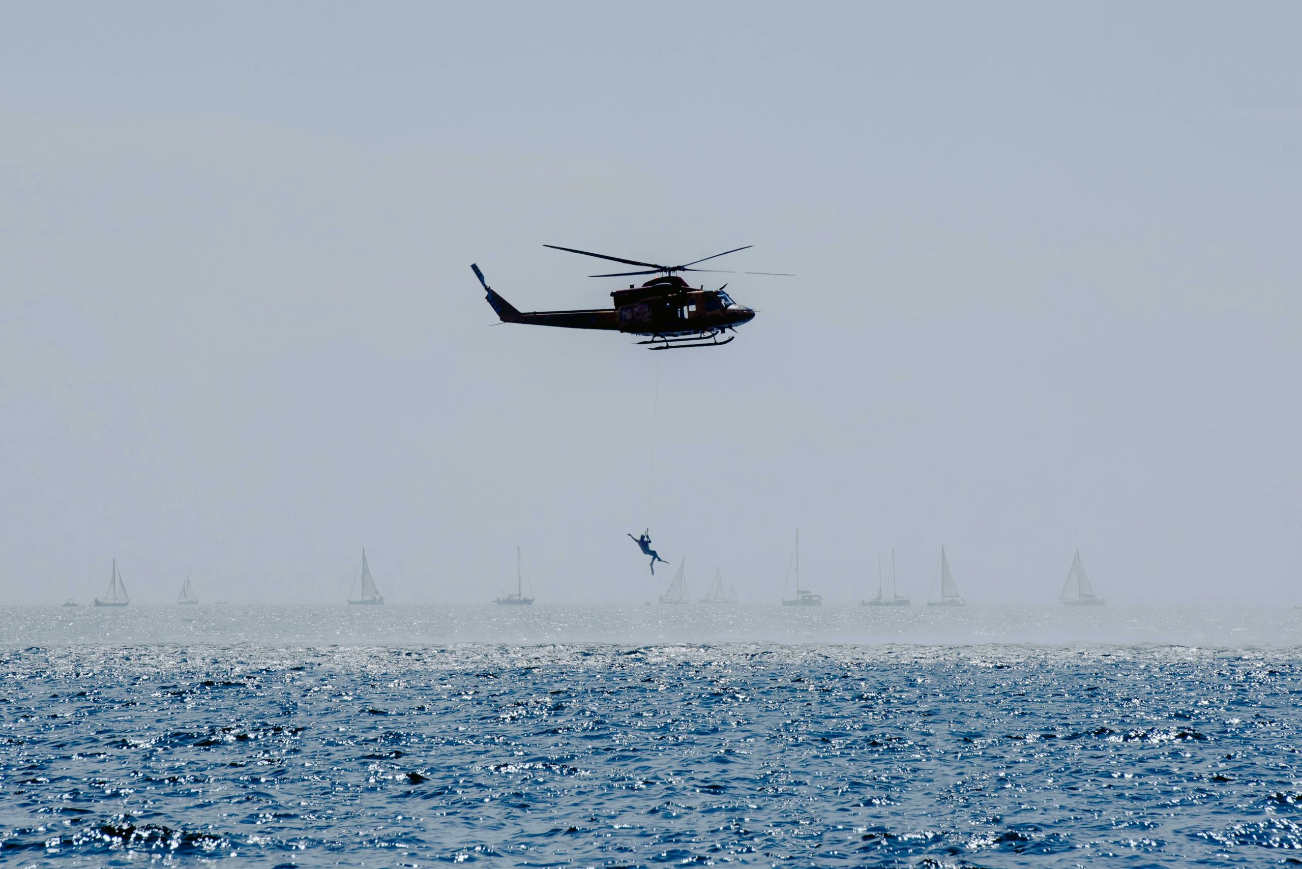 A helicopter flying over the ocean with waves visible below.